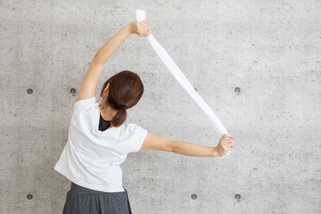 タオル肩甲骨開閉ストレッチをする女性